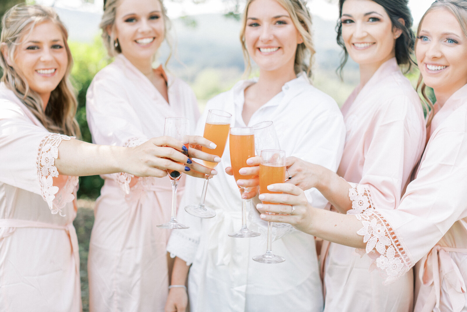 Bridesmaids toast to brides with mimosas