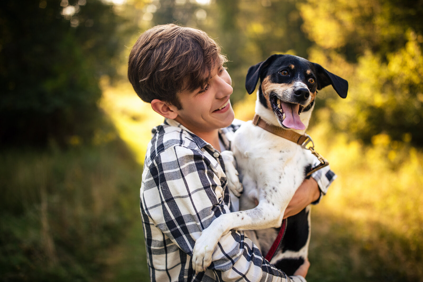 a senior boy holds his dog in the woods near pittsburgh.