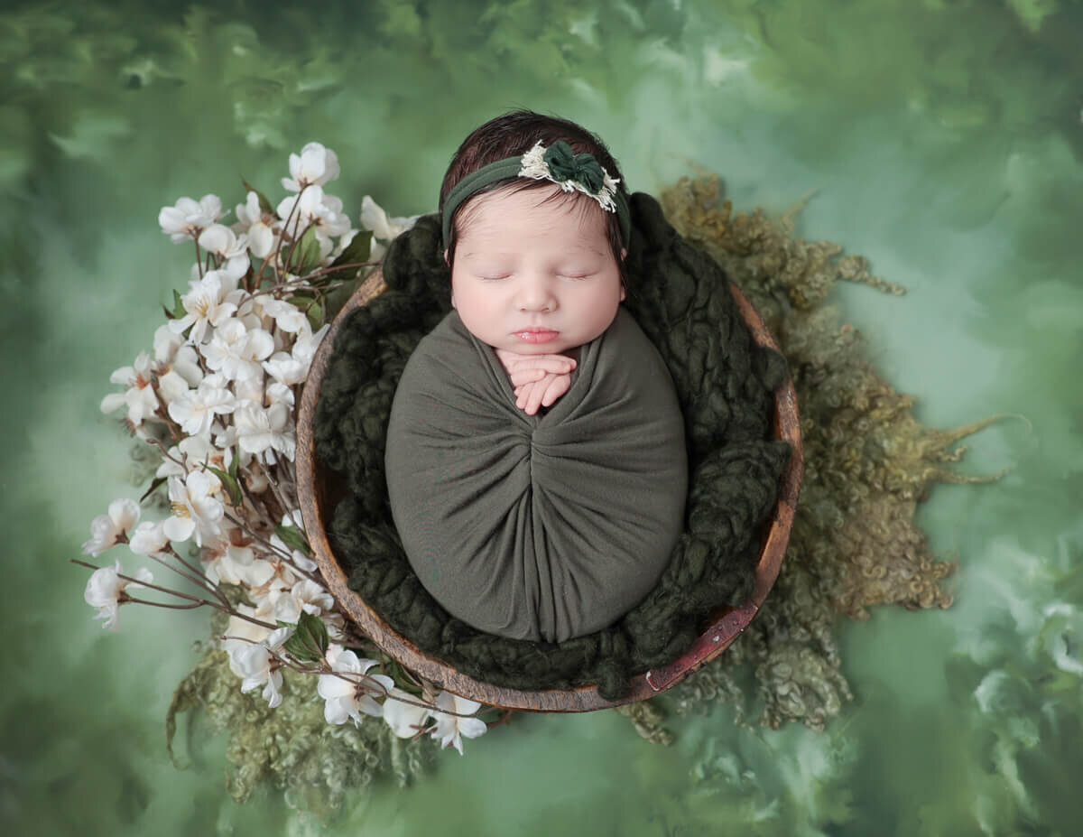 Newborn baby peacefully sleeping in a cozy woven basket during a photoshoot in Rochester, NY.