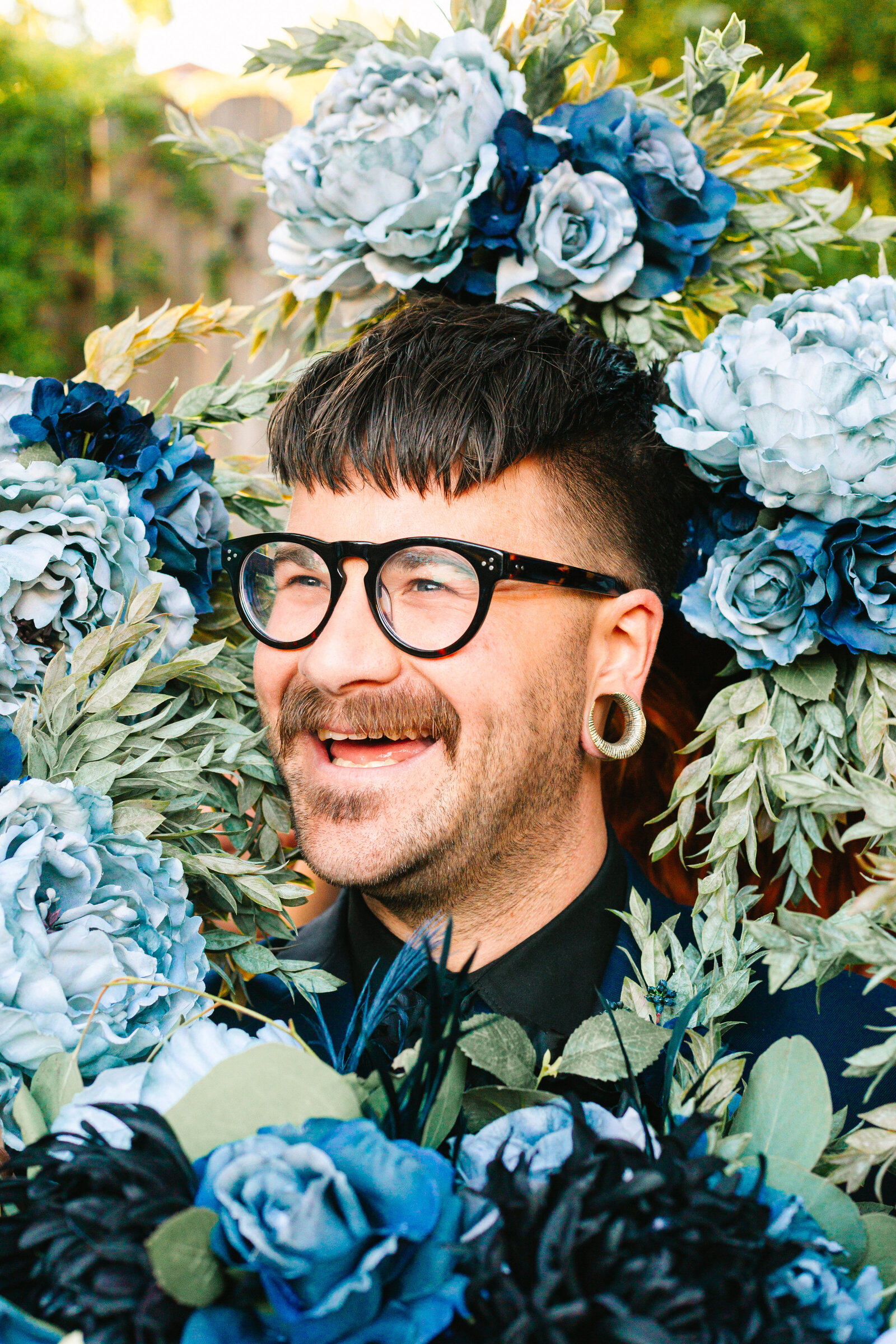 Tattooed groom with colorful wedding flowers.