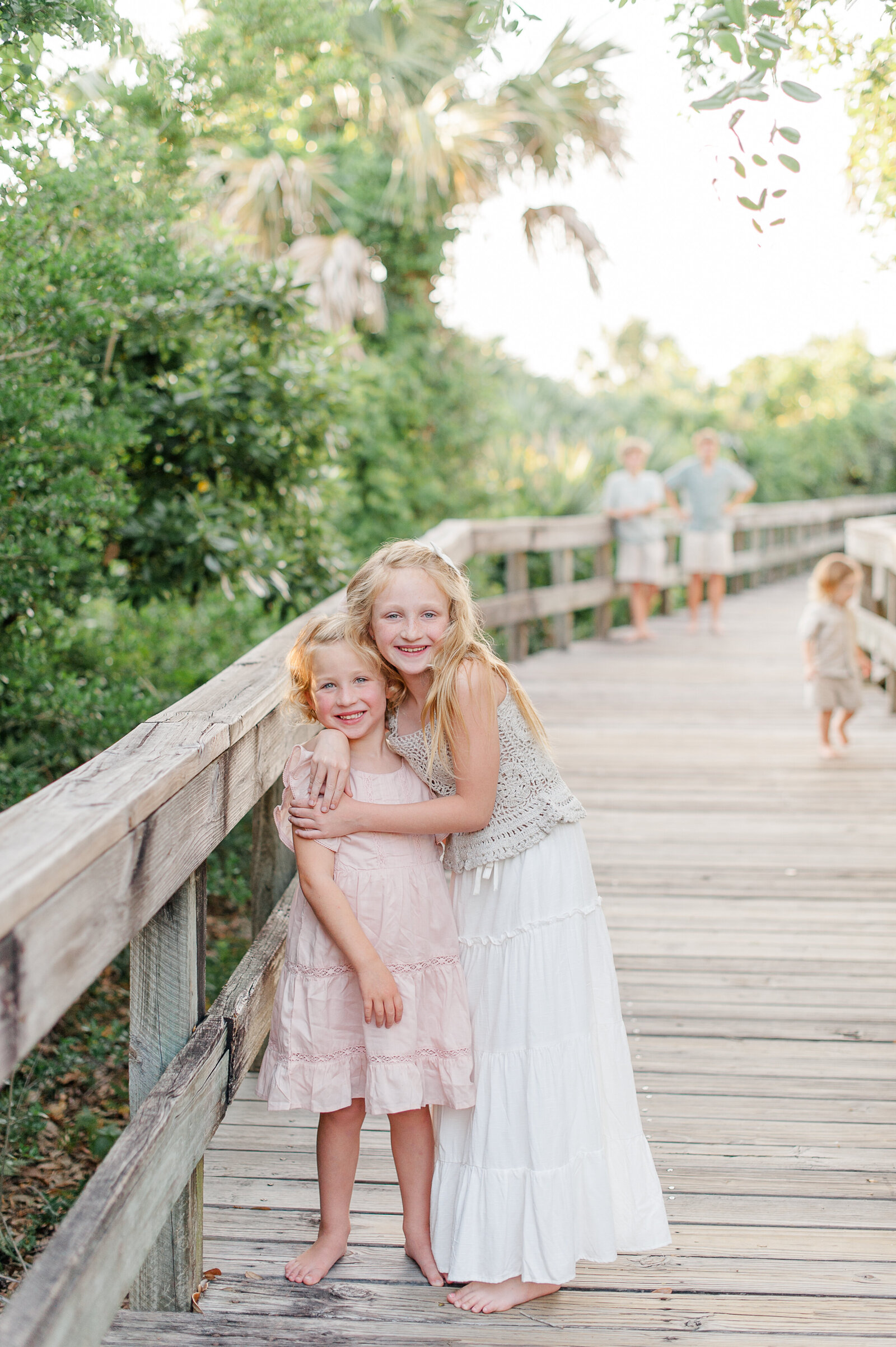 Young kids play on the boardwalk during their family photography session at sunset