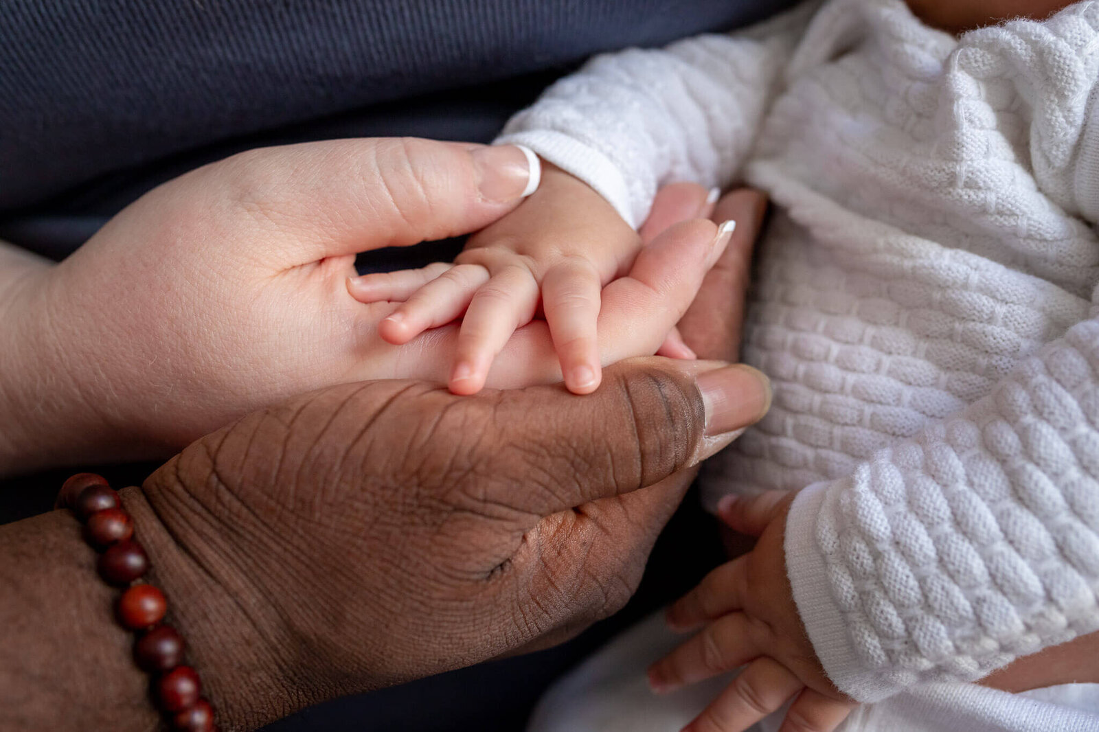 A close-up of mom and dad's hands holding their baby's hand during their Woodbridge newborn session.