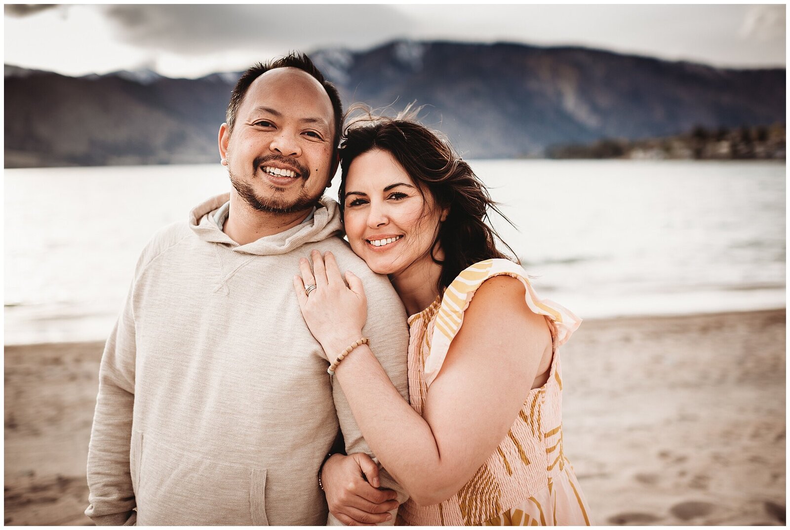 Couple in front of lake smiling at camera family photography