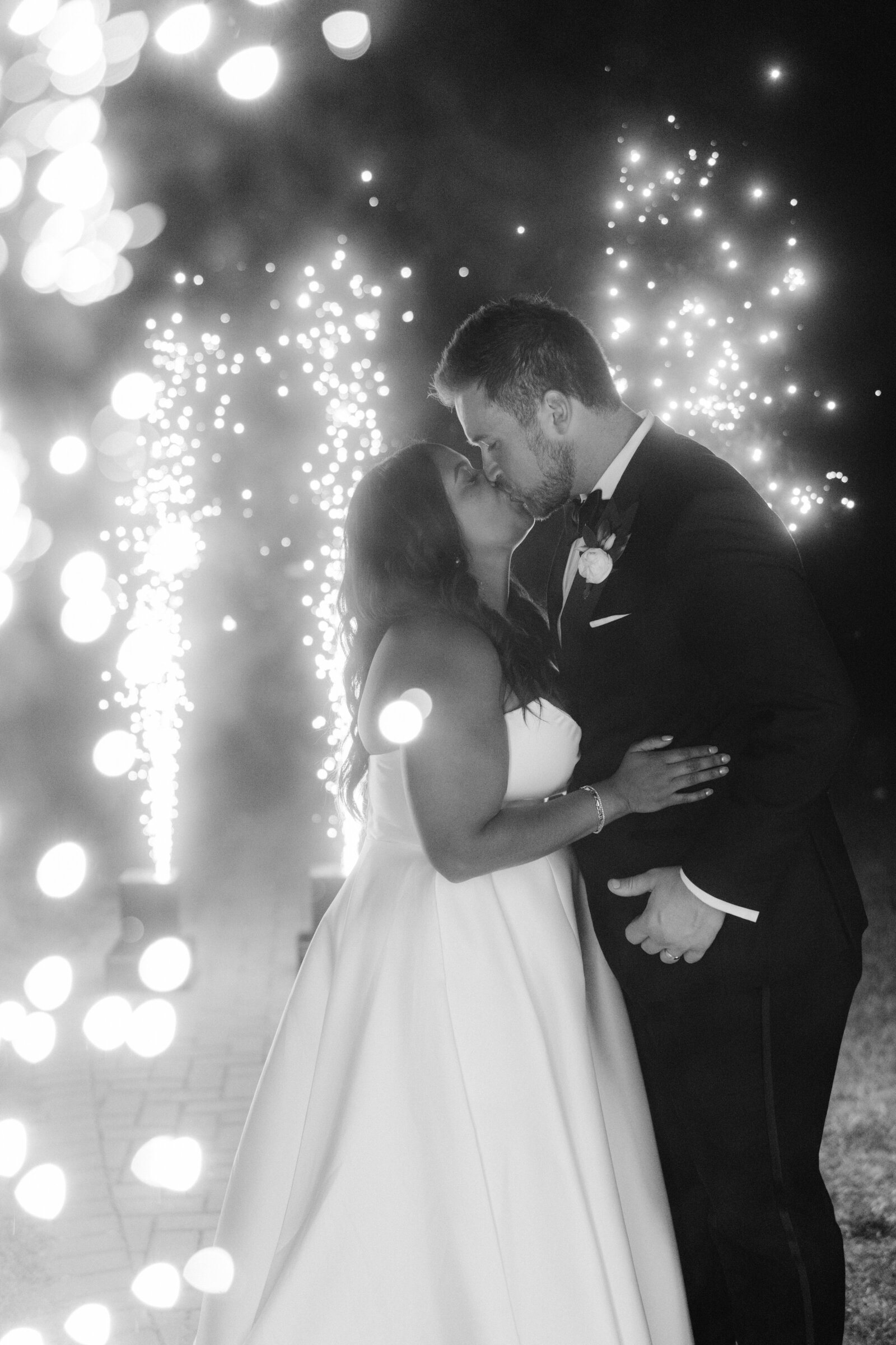 bride and groom kissing in front of sparklers