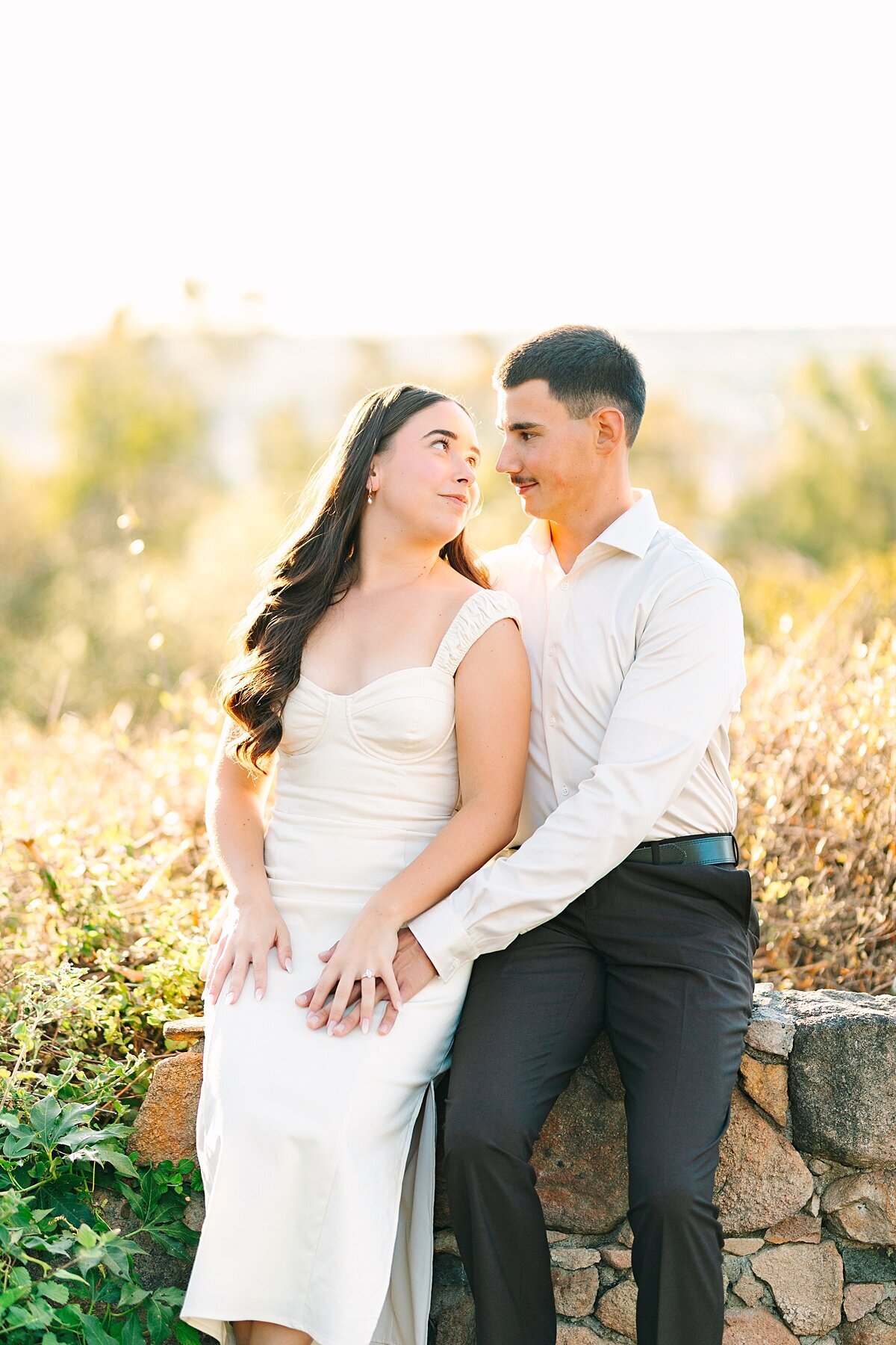 Engaged couple sitting together in the gardens during their engagement photoshoot at Alta Vista Botanical Gardens in Vista, CA.