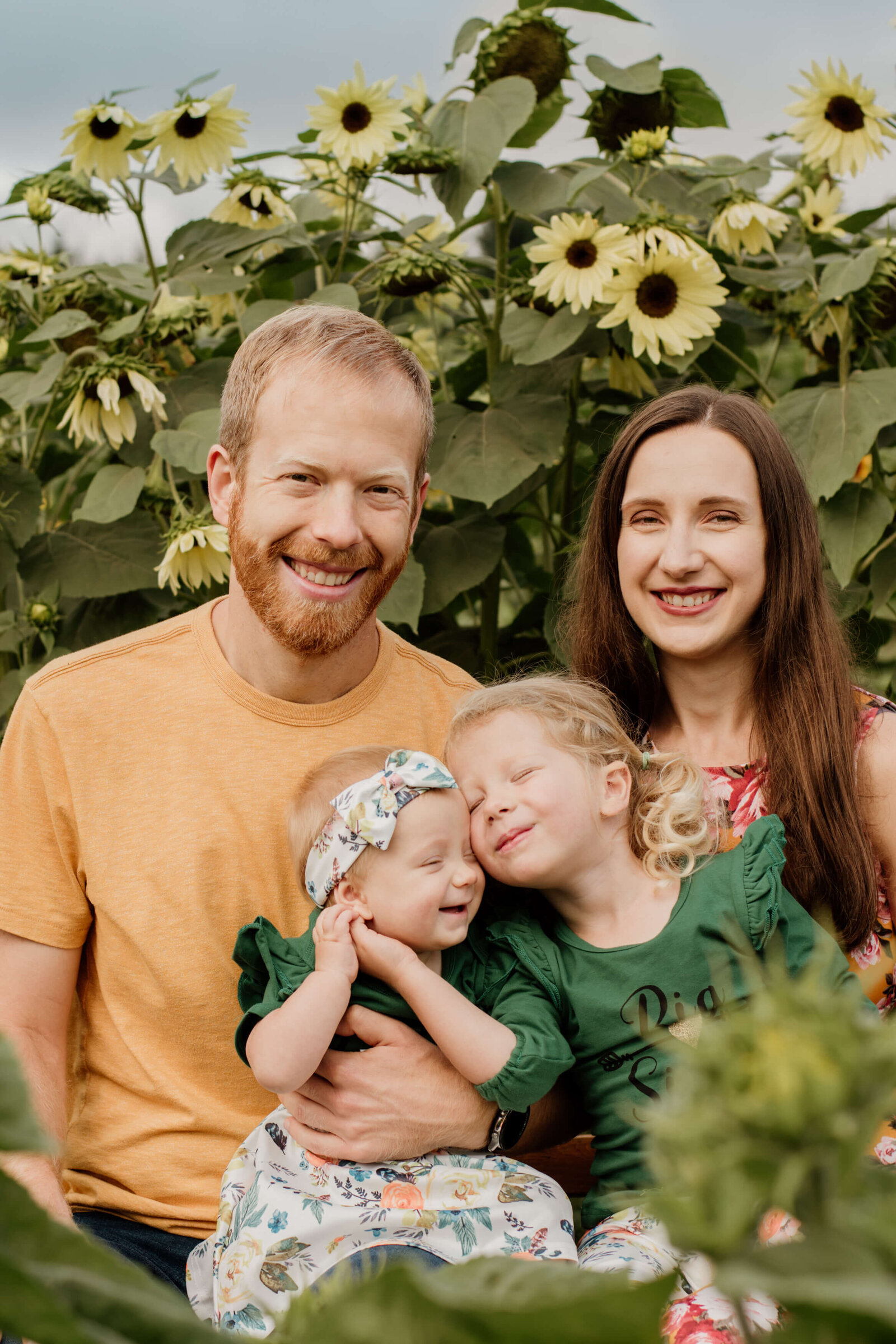 Family snuggles at sunflower field.