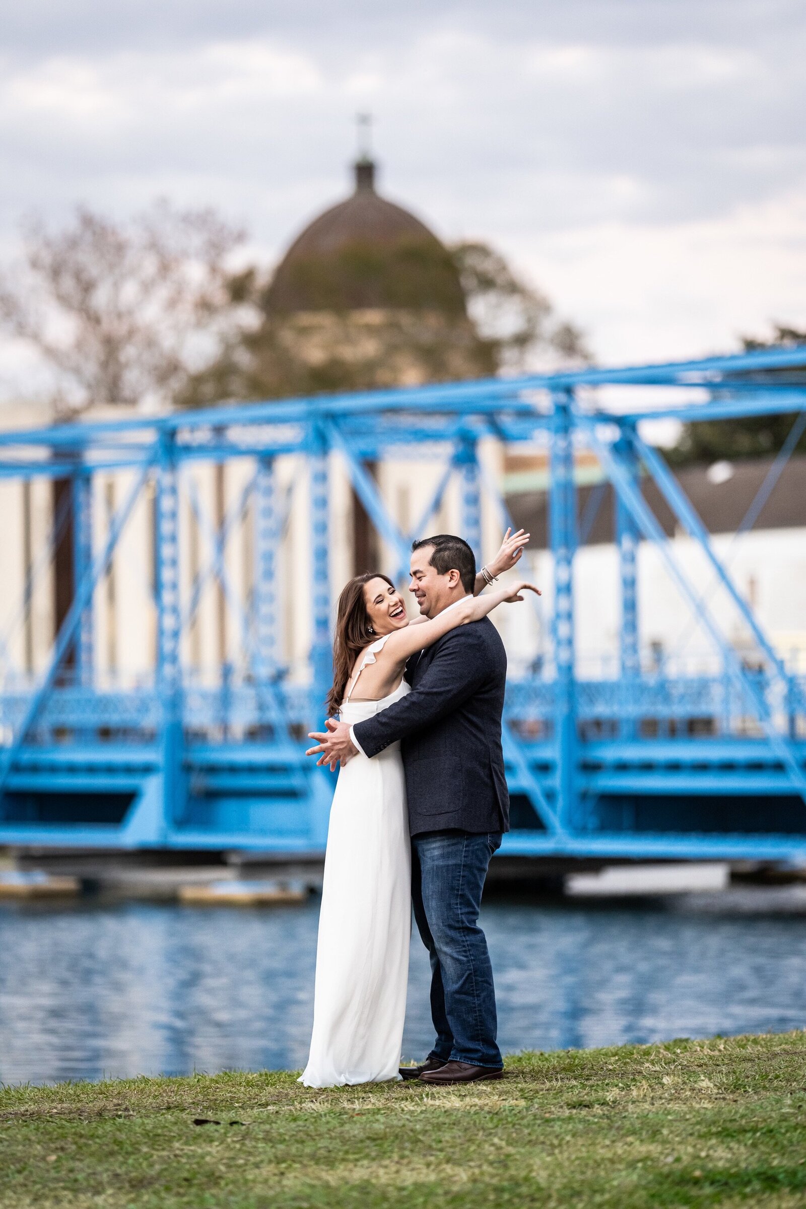 Engagement portrait of couple hugging with Cabrini Bridge in the background