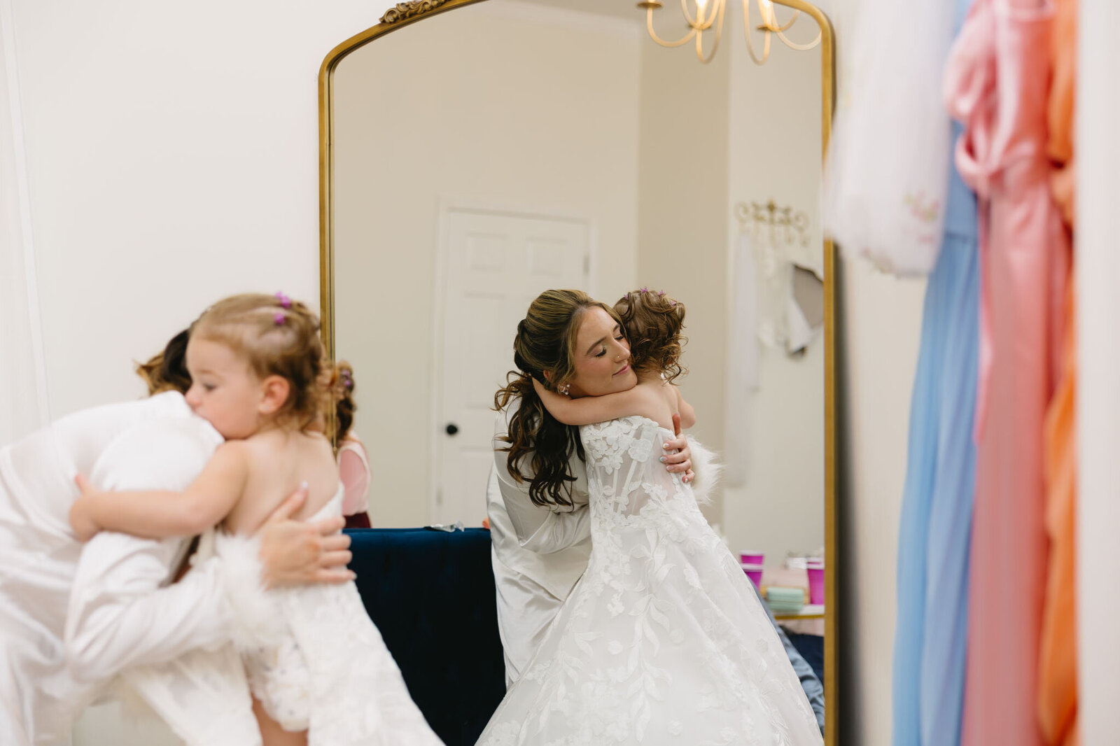 Bride hugging flower girl in mirror view