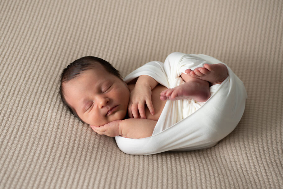 Sleeping newborn pose on back with hand on cheek