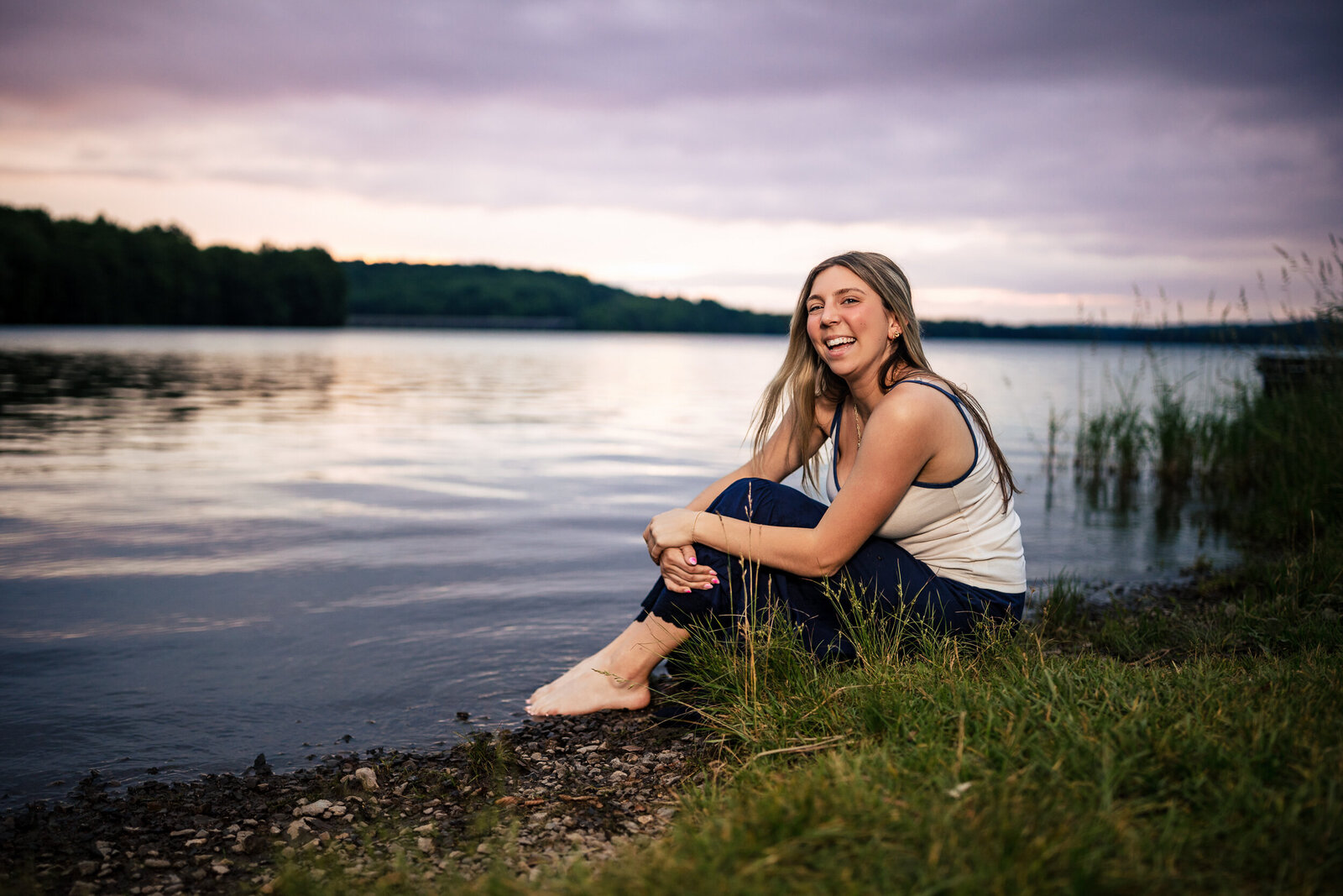 Senior wearing a flowy dress, sitting on the rocky shoreline at Moraine Lake