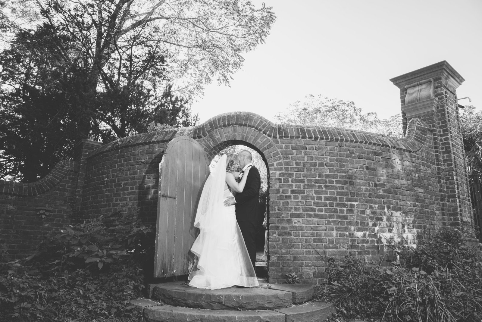 bride and groom kissing in brick archway at George Weir Barn