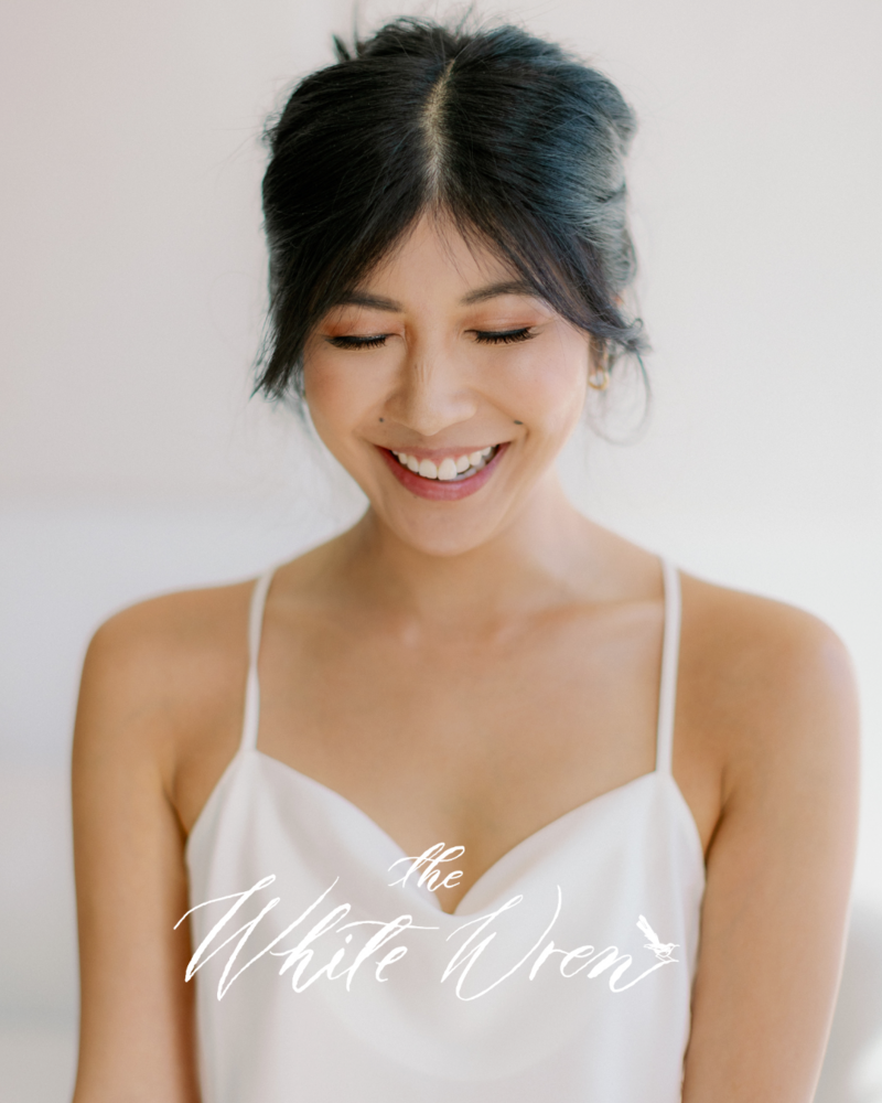 Kohnur bride with fresh natural makeup, soft eyeliner, and peach blush in minimalist indoor bridal editorial featured on The White Wren