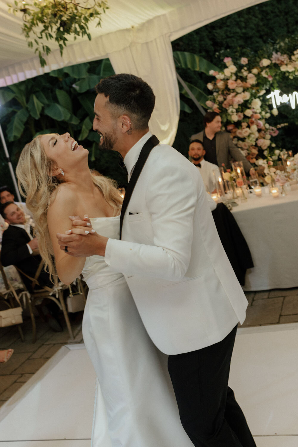 Bride and groom dancing under a floral backdrop