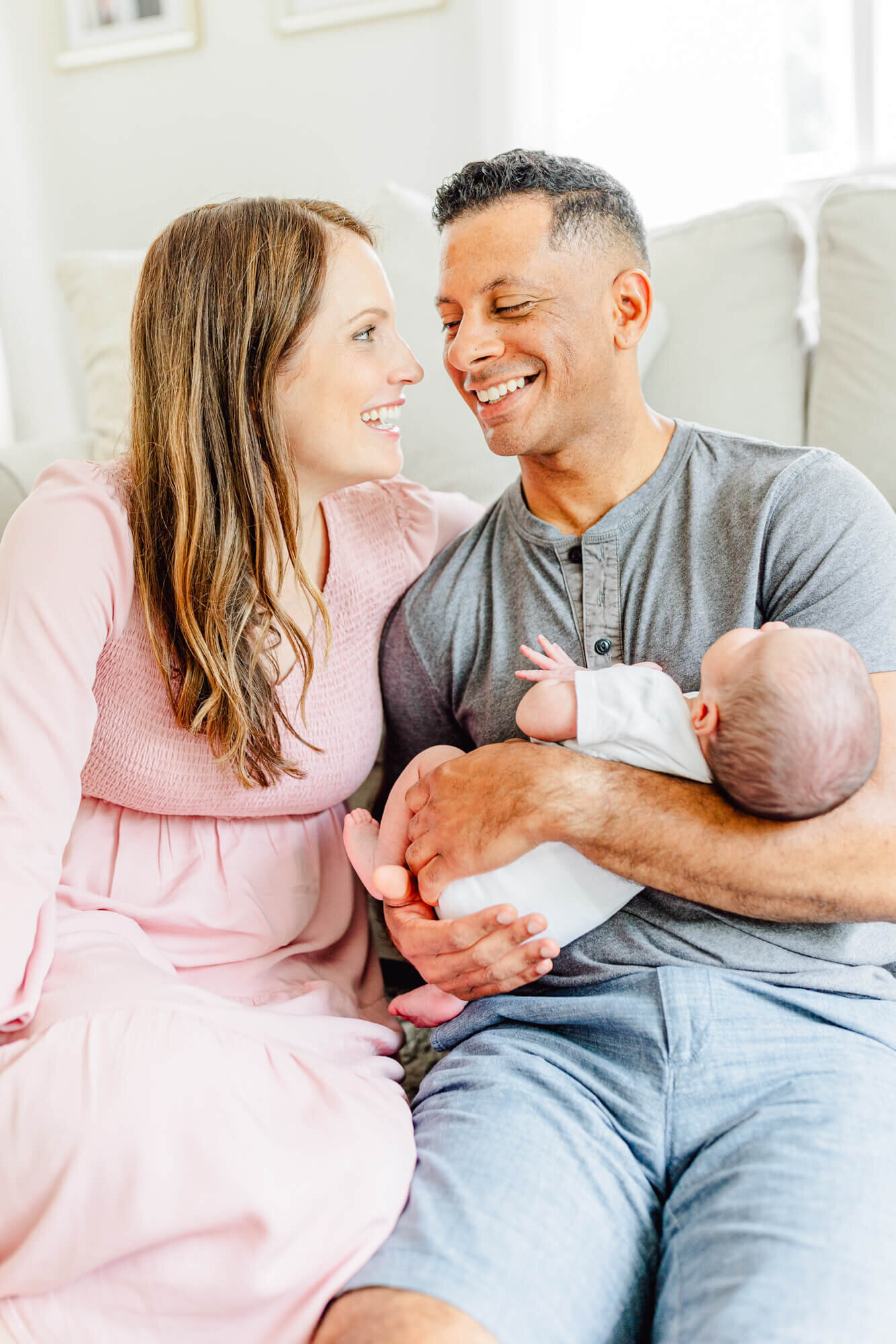 mom and dad talk/laugh while seated and holding newborn