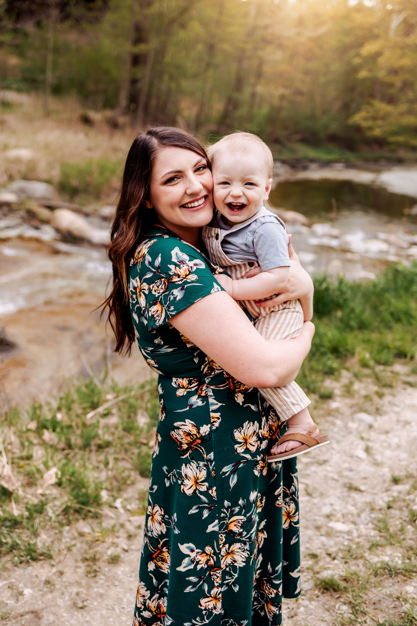 Mother snuggles her baby boy in front of a flowing stream at Wintergreen Gorge