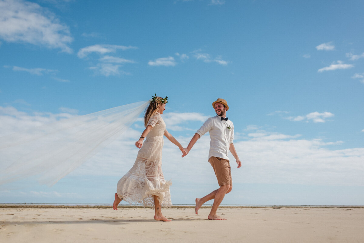 bride and groom running on the beach