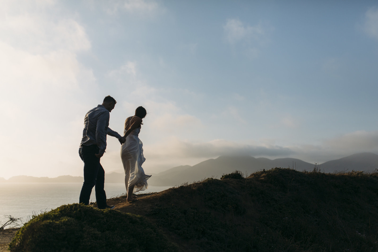 couple climbing mountain in wedding attire for San Francisco elopement photographer My Sun and Stars Co near the Golden Gate Bridge