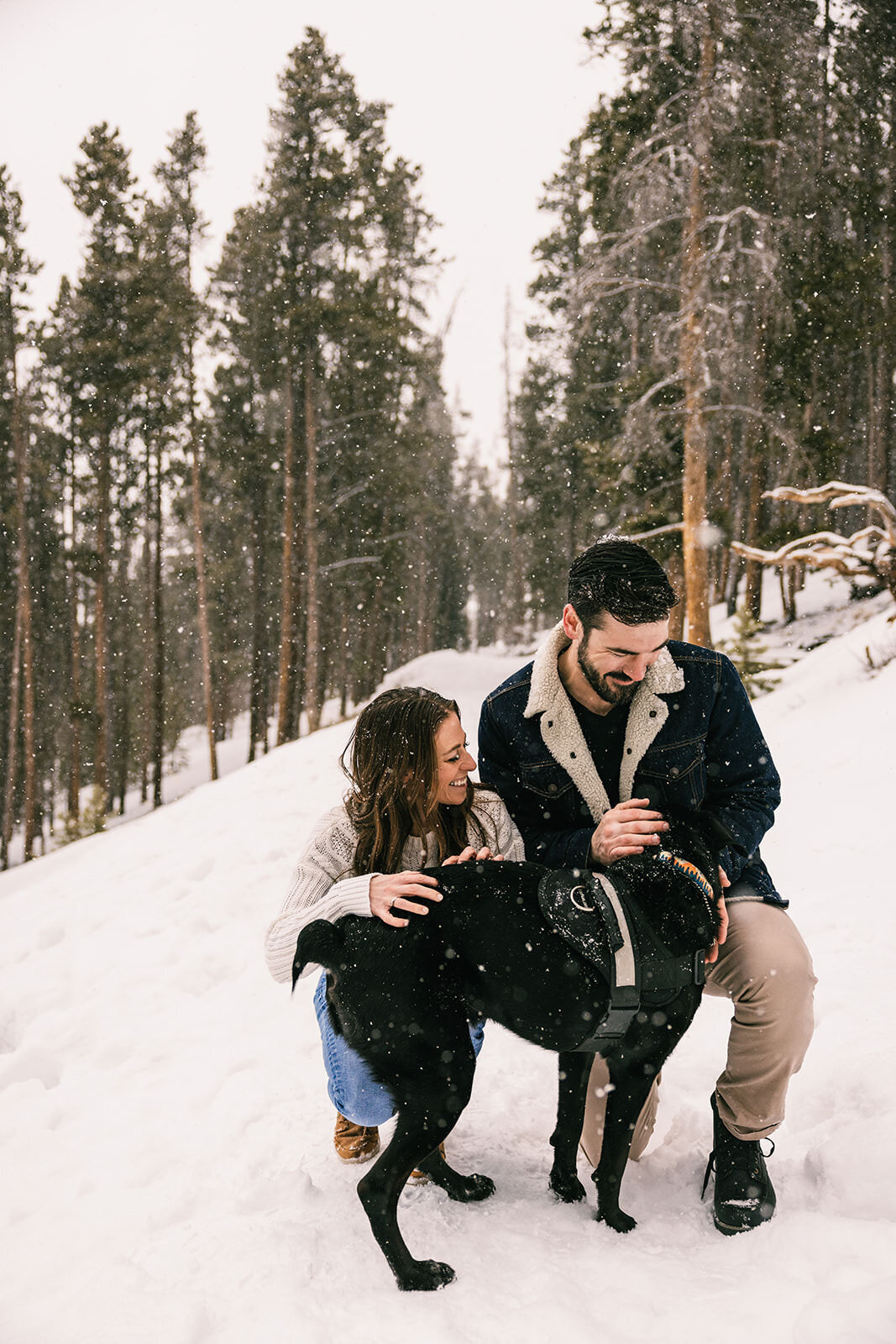 Couple snuggling with dog in the snow during photo session in Breckenridge, Colorado