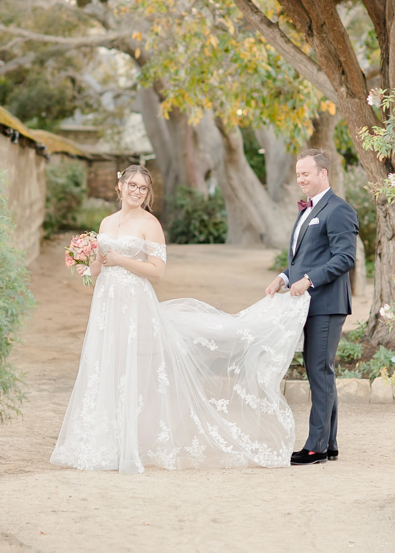 groom walking with bride while he's holding her dress at their monterey wedding at The Barns