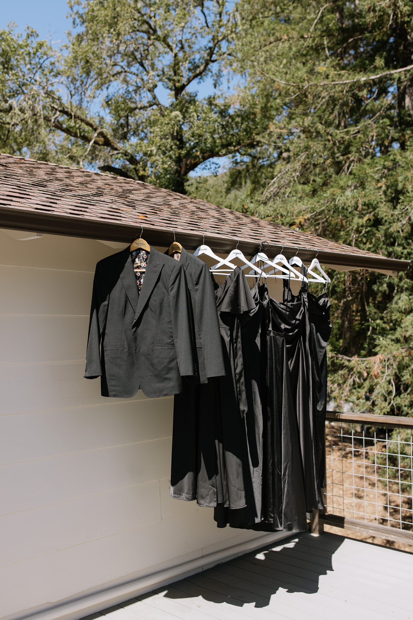 Groom suits and bridesmaid dresses hanging from exterior of getting ready suite at Nelson Family Vineyards in Ukiah, CA