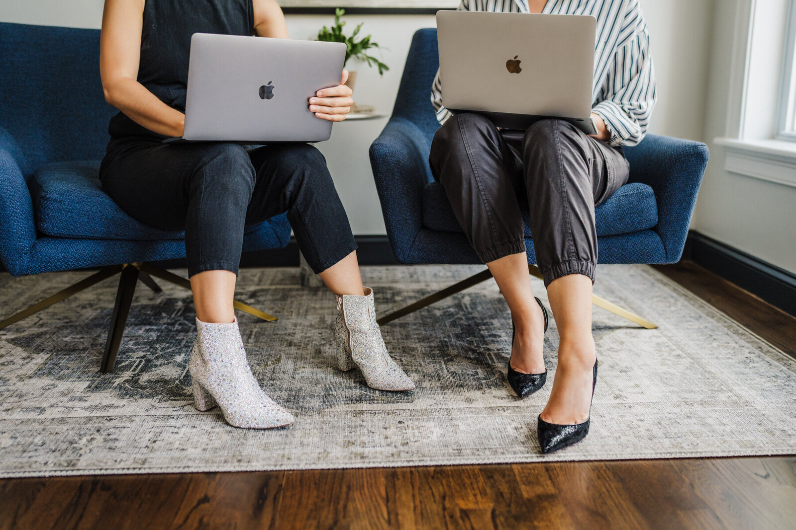shot of the feet of two women in heels working on laptops