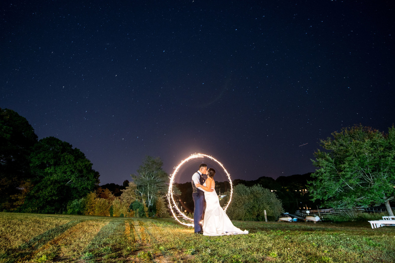 Bride and groom kissing outside in dark at Camp Pa-Qua-Tuck