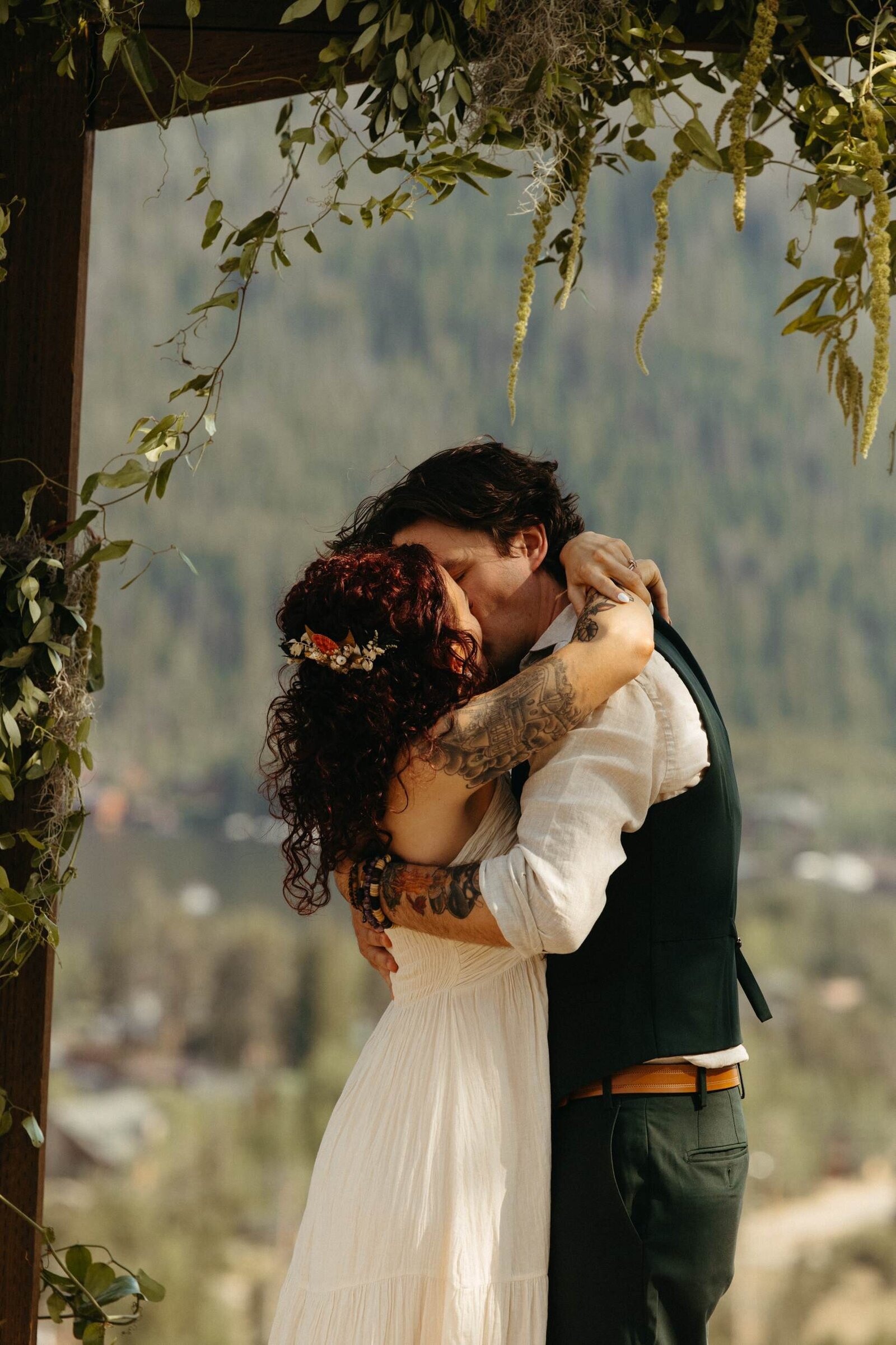 Bride and groom embrace and share their first kiss at the end of their wedding ceremony, mountains and lake in the background