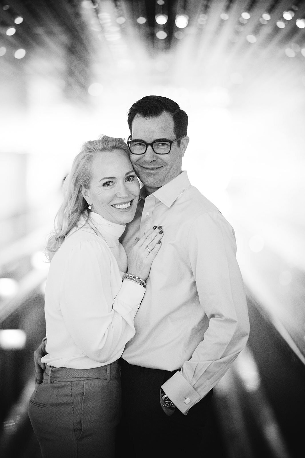 Joyful black-and-white couple portrait under a light installation, exuding warmth and connection.