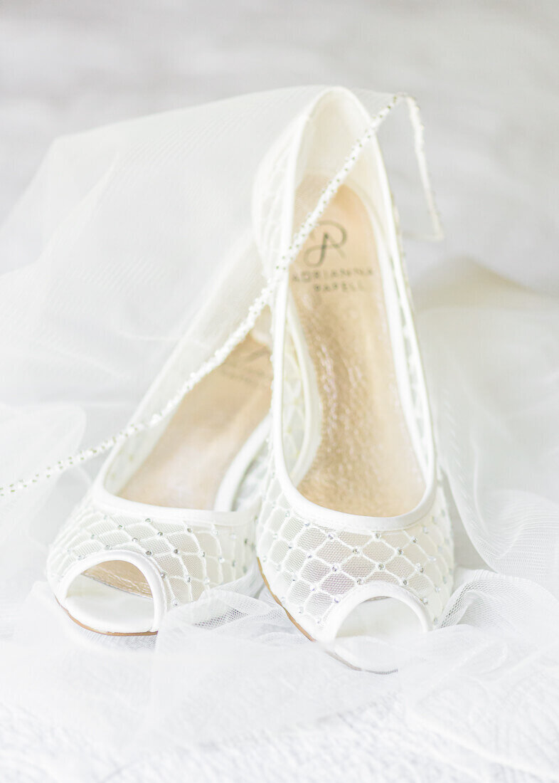 Salt Lake Wedding photography of open toed off-white Adrianna Papell wedding heels surrounded by a wedding veil.