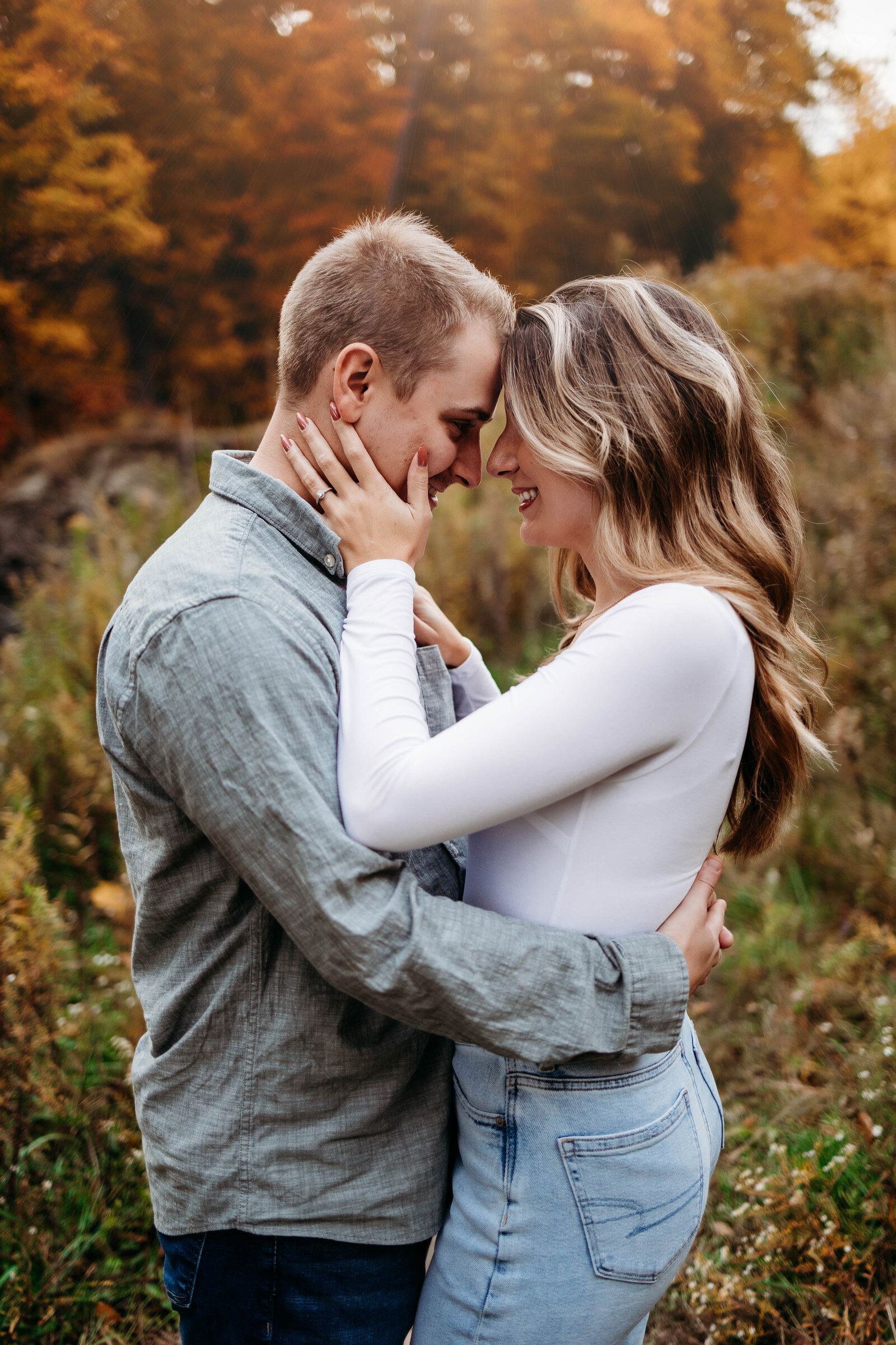 Couple holds each other close amongst beautiful fall foliage