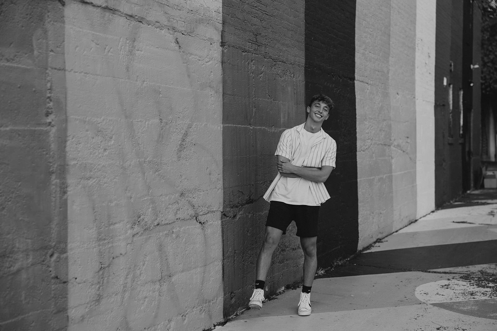A senior boy casually leans against an urban wall downtown Grand Rapids.