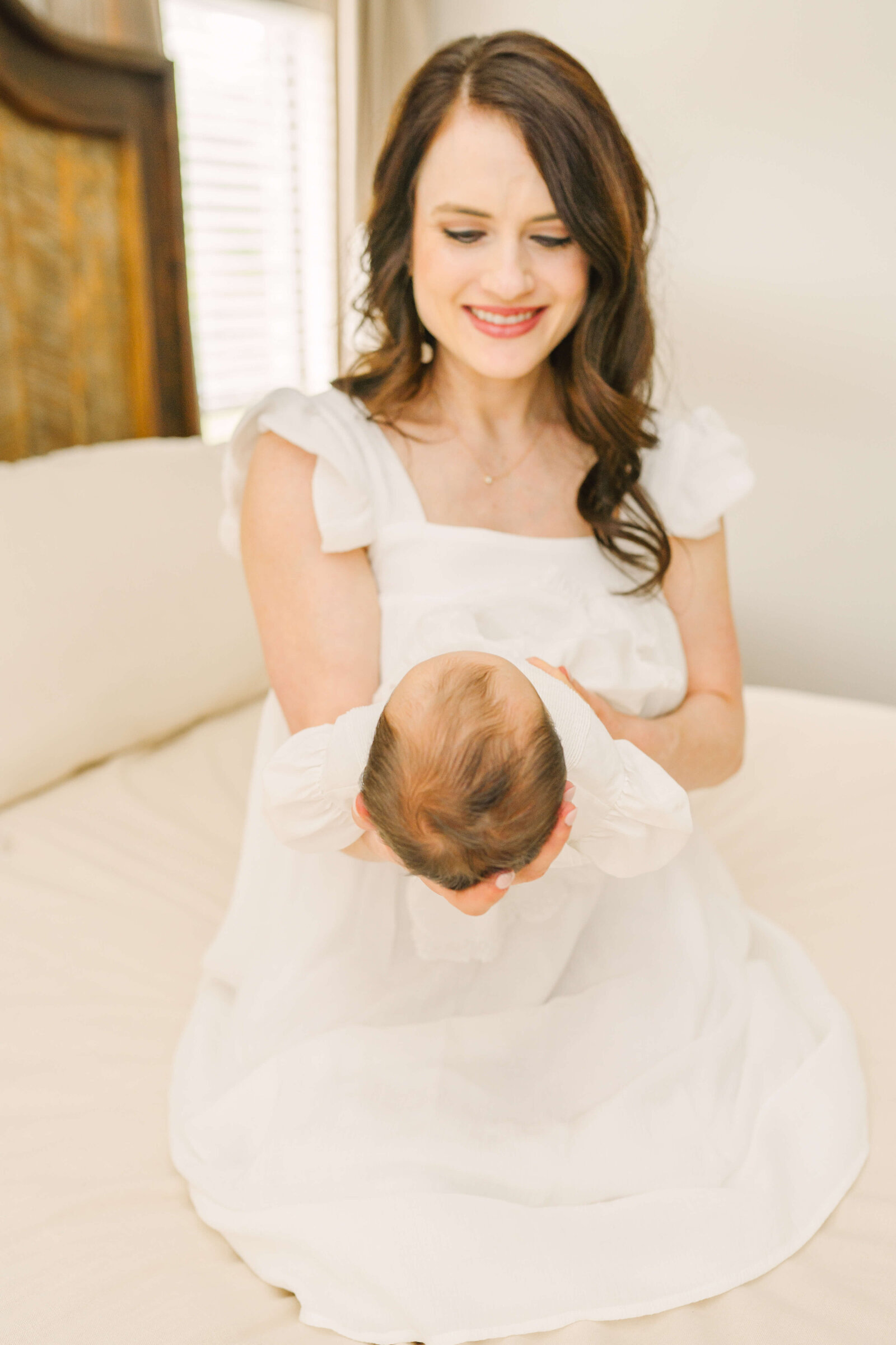 Mom sitting on bead holding baby in front of her