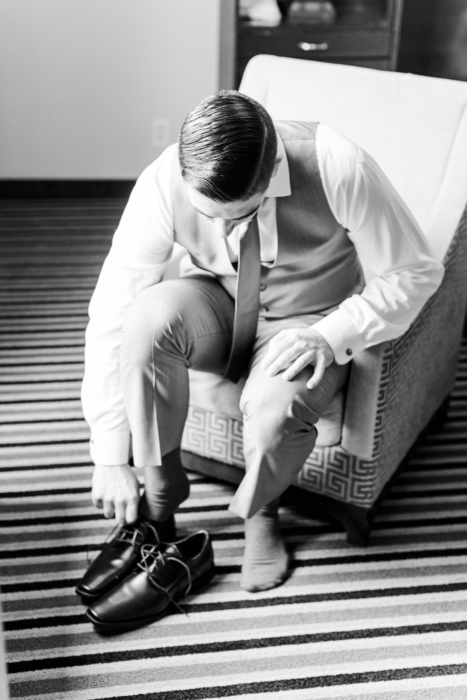8_groom_putting_on_shoes_in_hotel_room
