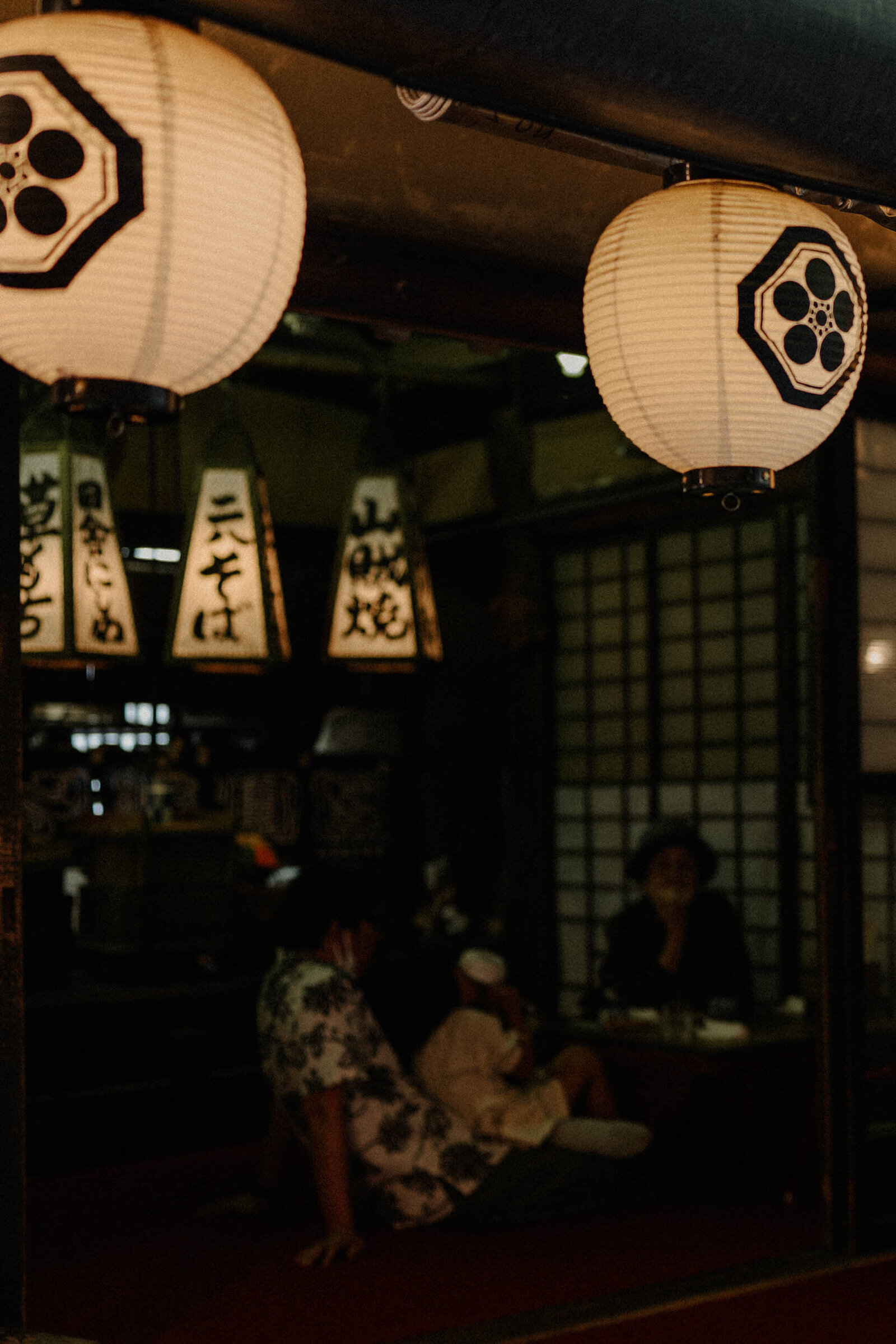 Moody nighttime photo of a Japanese restaurant lit by  lanterns, creating a cozy, intimate vibe.