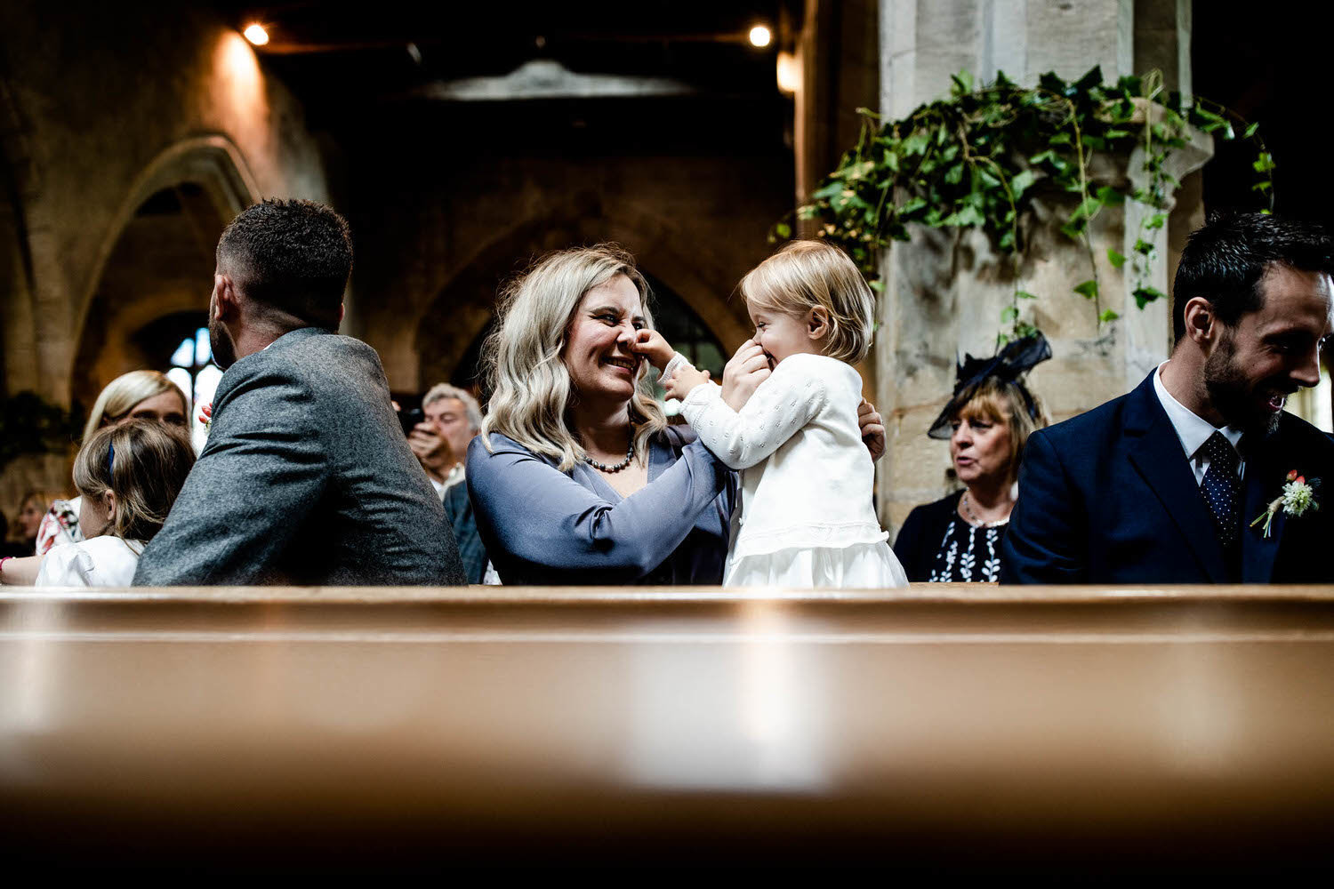 mother squishing noses with her daughter in church wedding ceremony