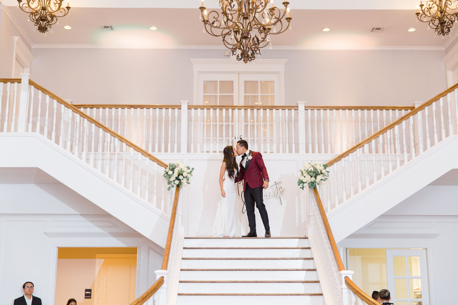 A couple kiss on the staircase landing in the ballroom.