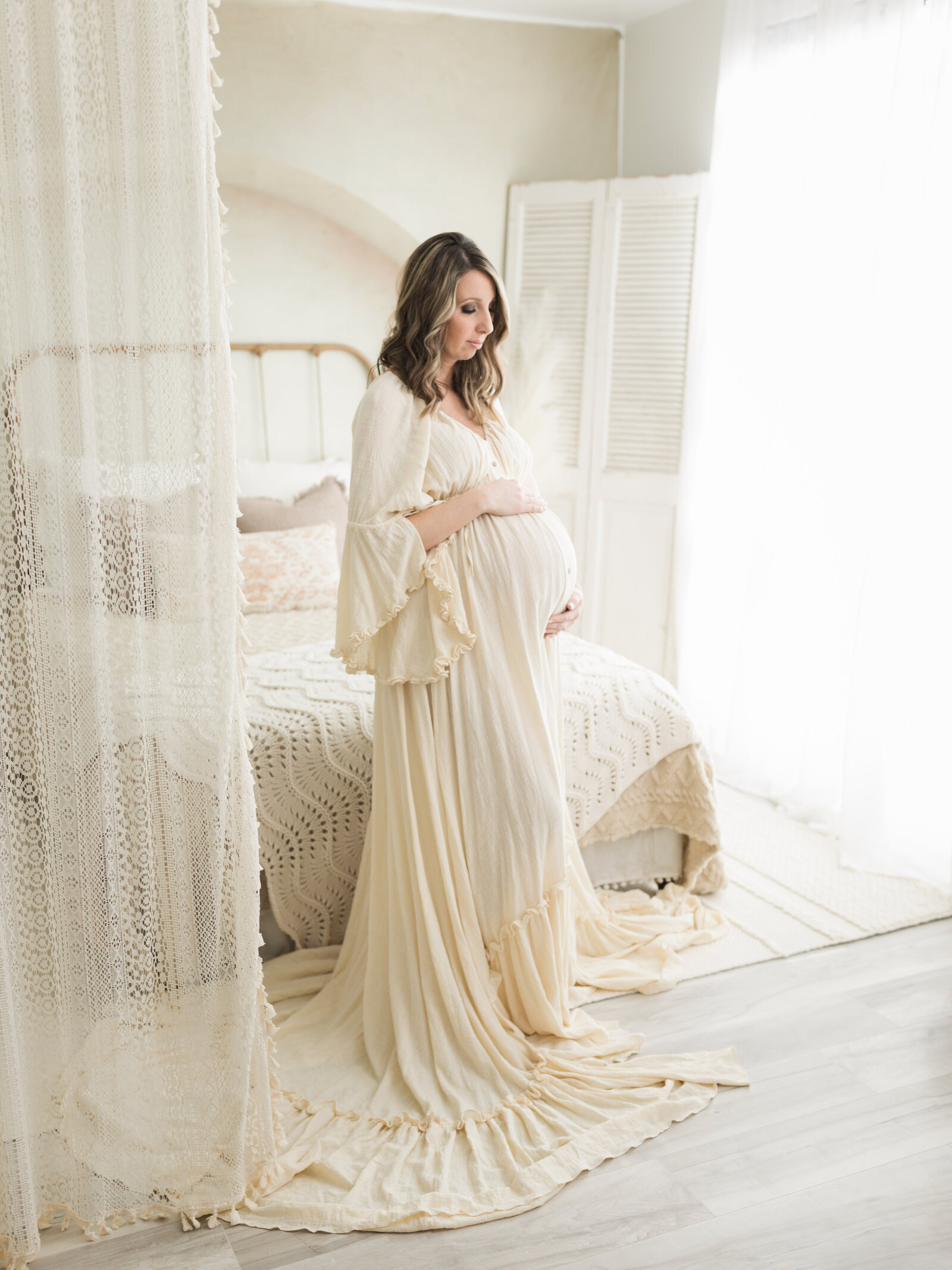 pregnant mother in cream maternity gown holding baby bump for maternity photoshoot