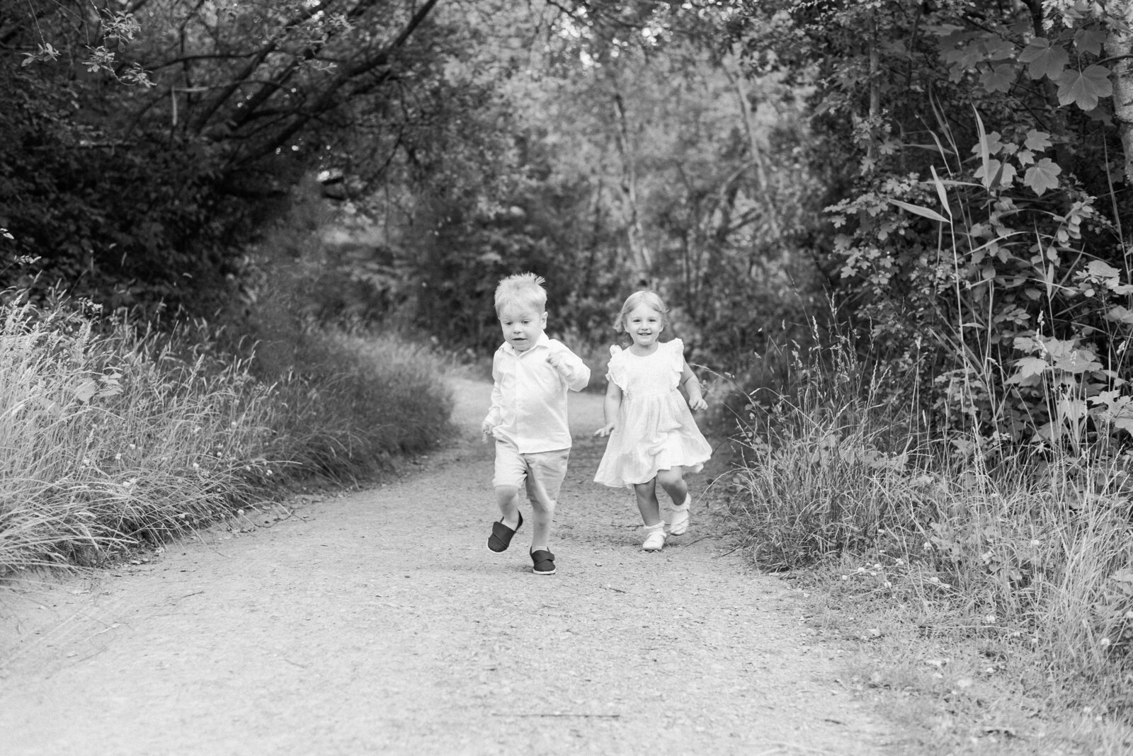 A girl and boy running through the woods in billingshurst family photoshoot