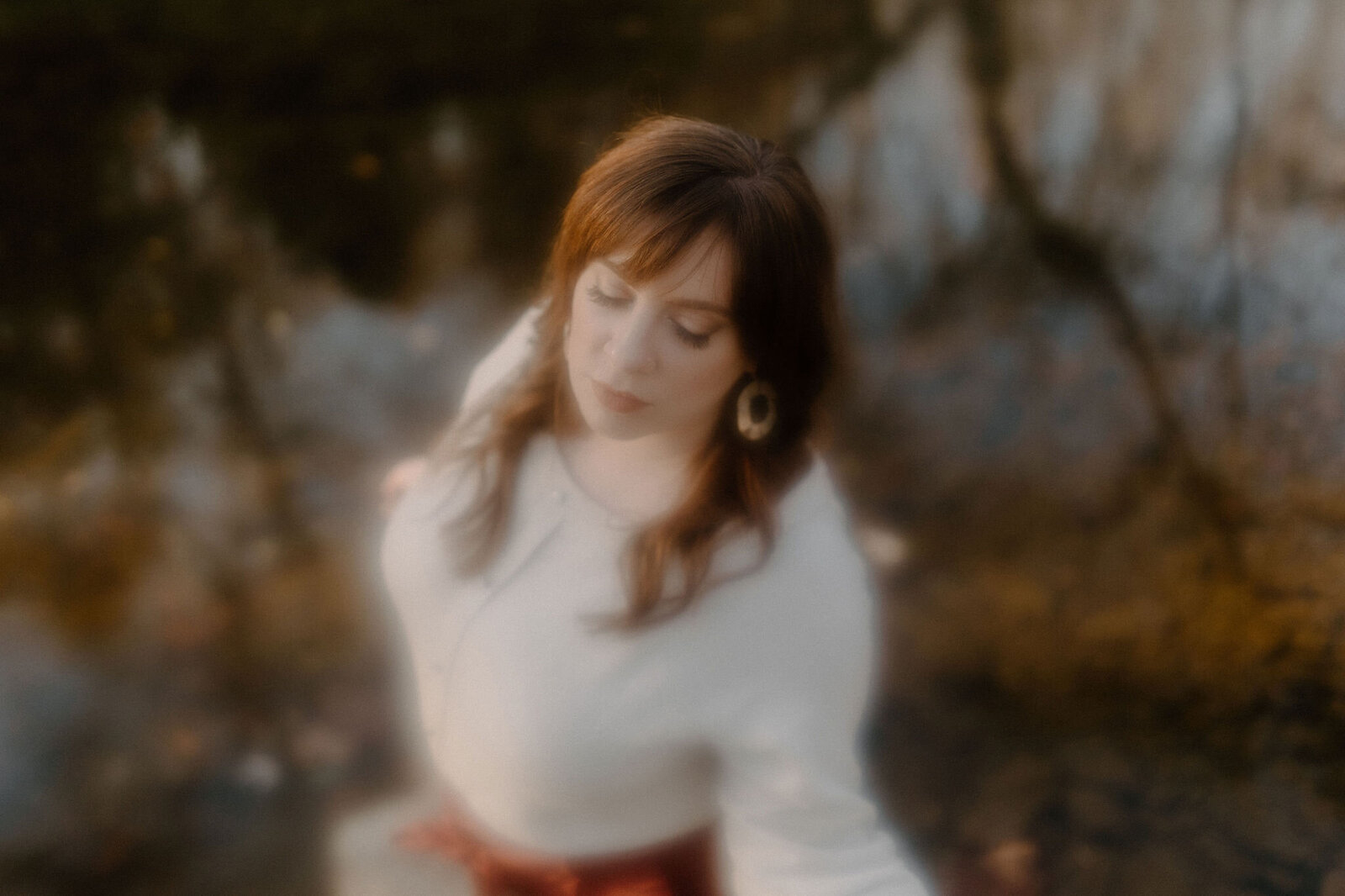 blurred lens outdoor brand photo of woman with lake reflection of autumn leaves and trees