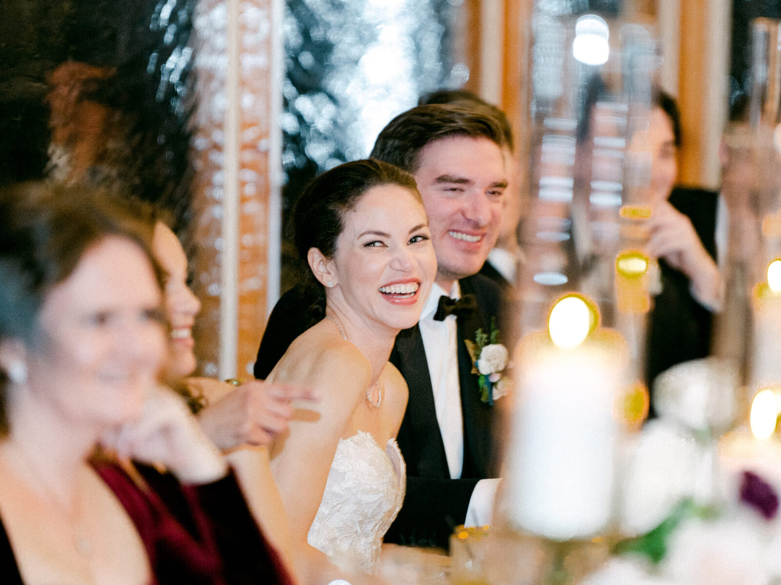 Bride and groom smile during dinner at wedding reception.