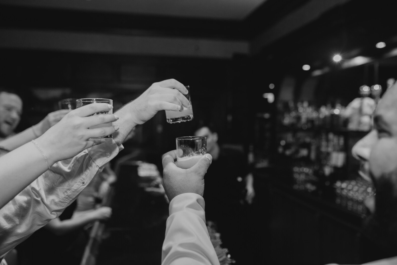 group of people cheersing at bar with shots
