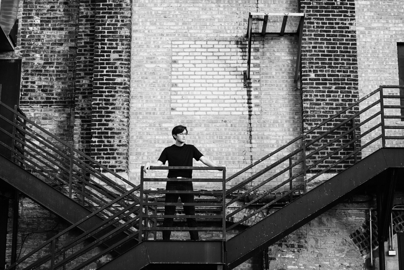 high school senior boy on staircase in front of urban brick wall