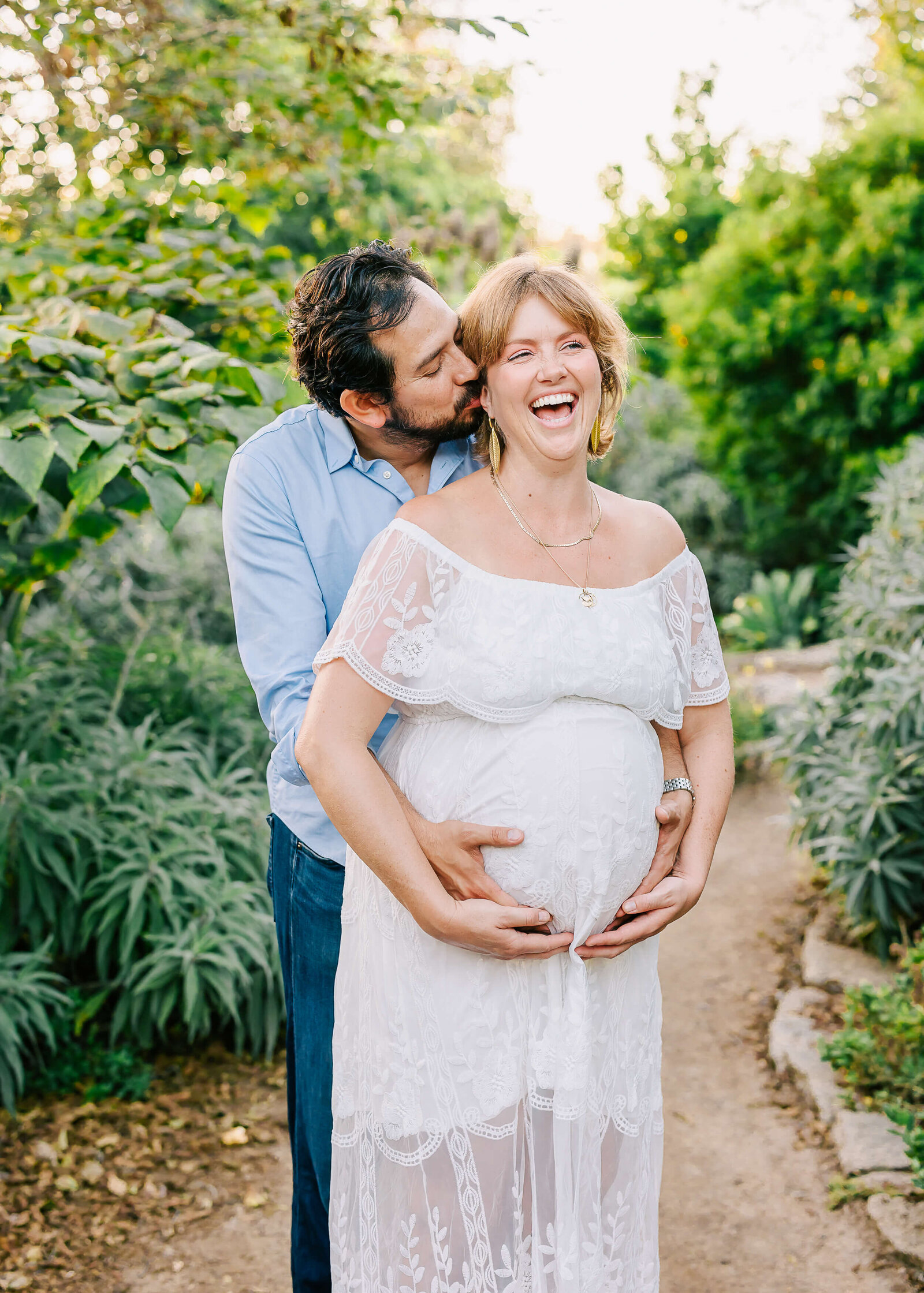 Couple embraced laughing during maternity session by Ashley Nicole Photography in Huntington Beach.