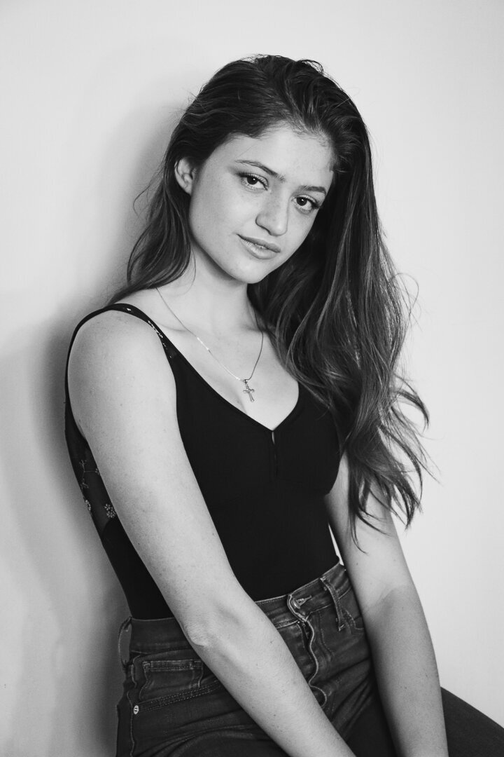 girl sitting against a wall looking at the camera