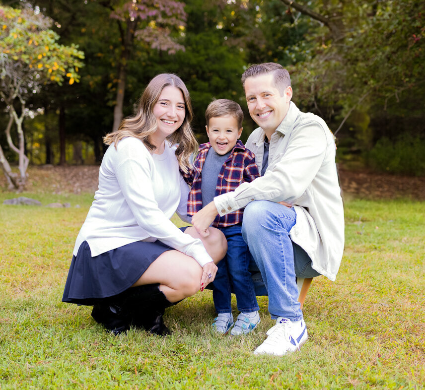 Family squatting down in the grass during a fall mini session in Waldwick, NJ