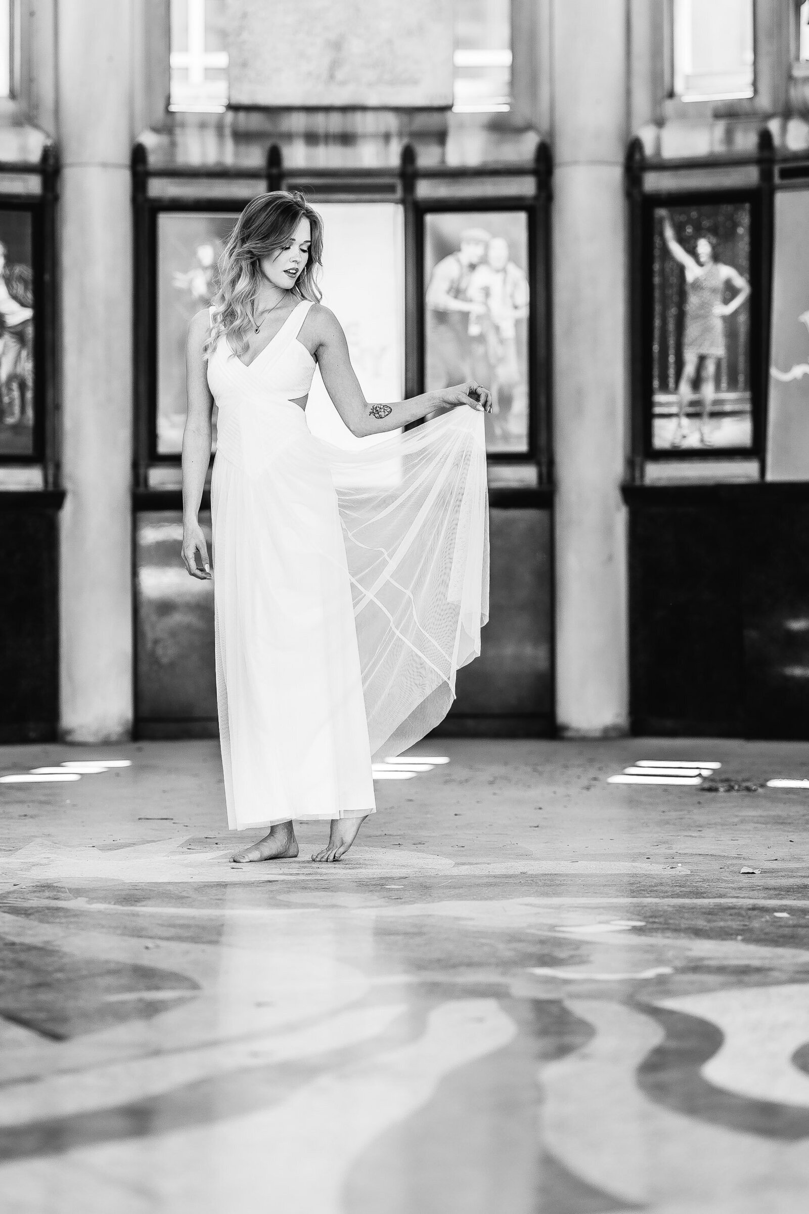 senior holding dress in one hand and looking at the ground at st. louis muny