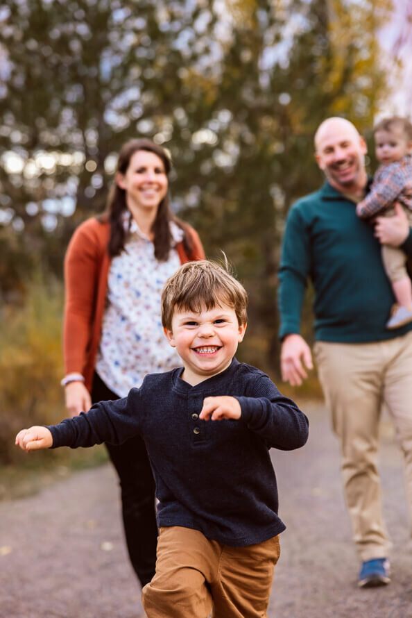 Boy runs toward camera smiling during his family photos at Fly N B park.