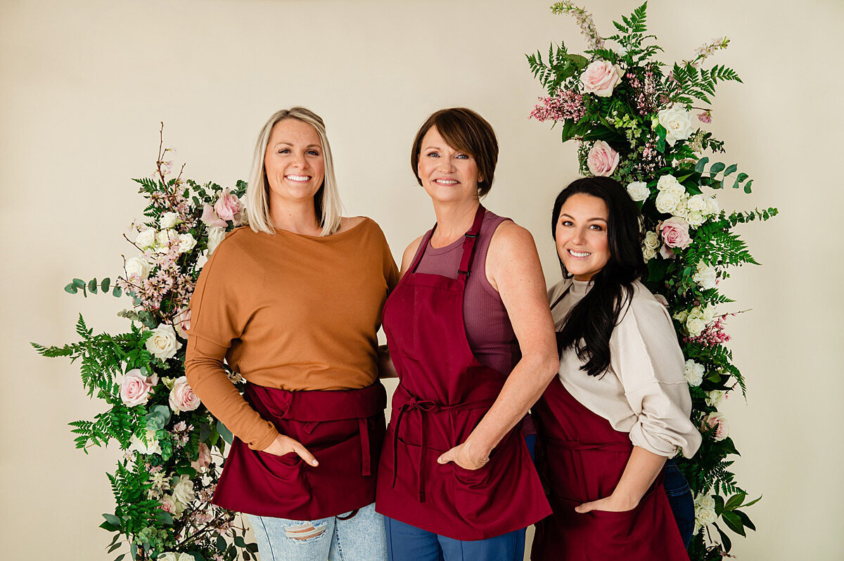 Florists wearing red aprons and smiling at the camera