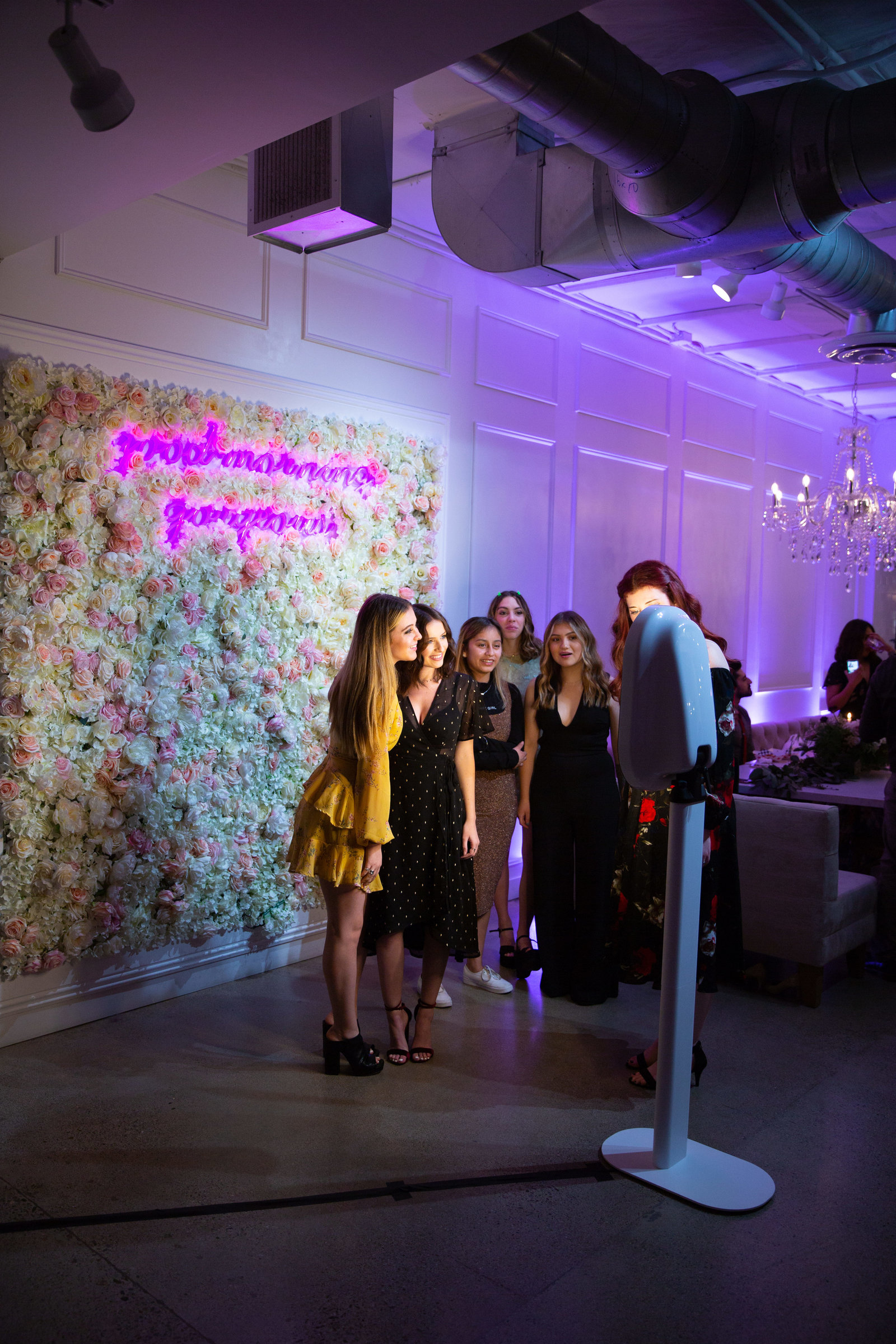 Group of friends laughing and posing with props in the photo booth at an event