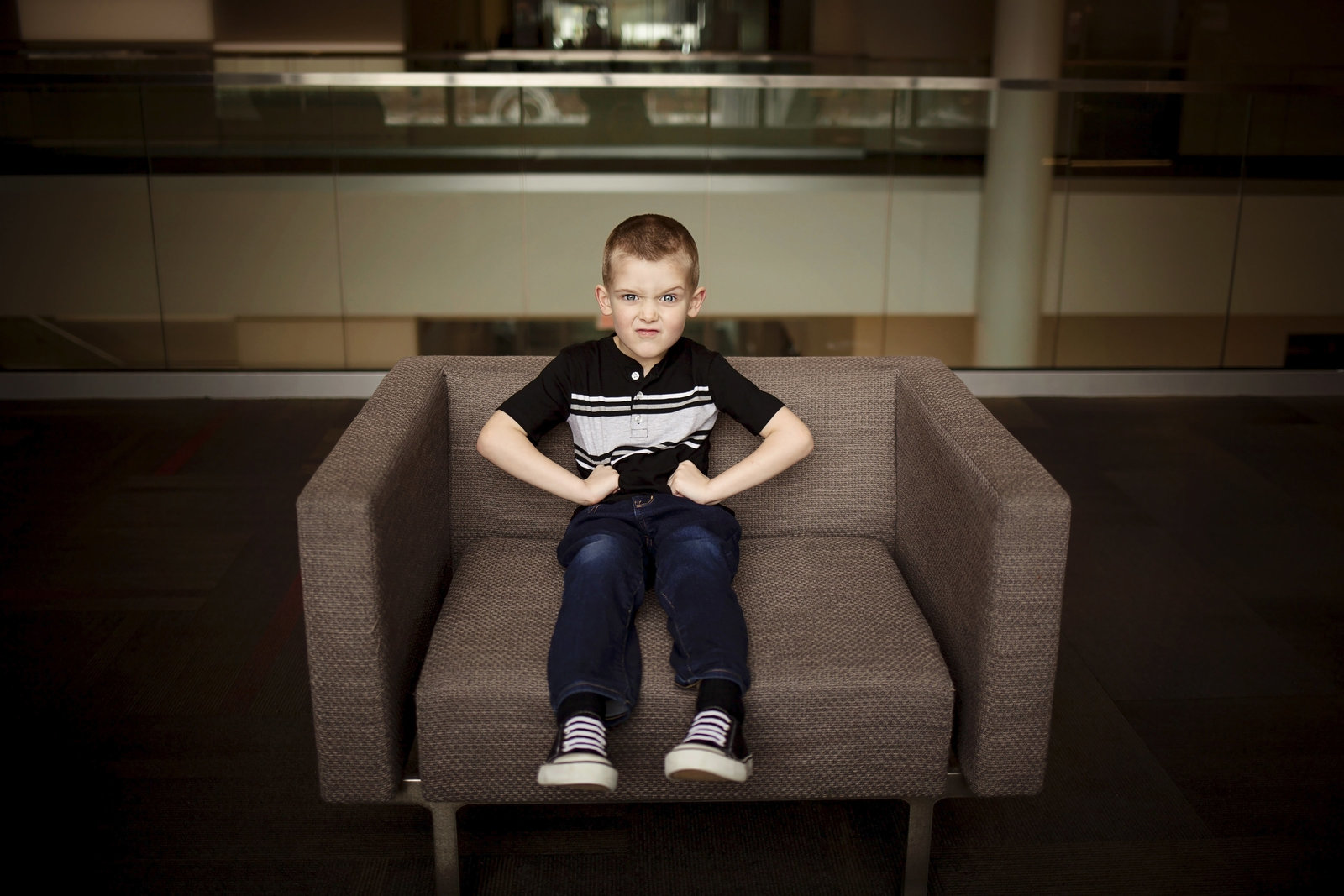 Boy sitting in chair flexing his muscles and making a silly face.